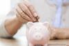 senior woman hand putting money to piggy bank