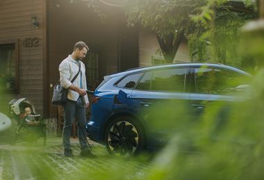 Business man charging EV with baby in background (1)
