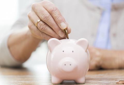 senior woman hand putting money to piggy bank