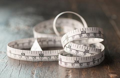 Close up tailor measuring tape on wooden table background. White measuring tape shallow depth of field.