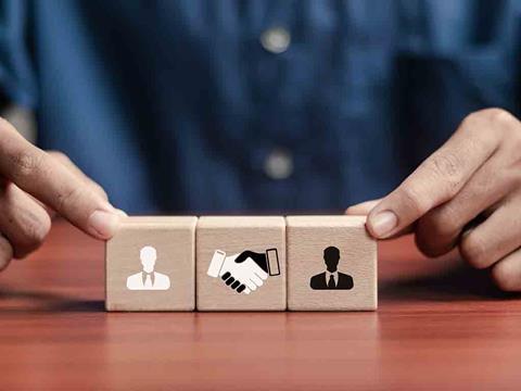 wooden block with hands shaking, symbolising an acquisition