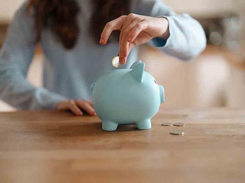 a person putting a coin into a piggy bank