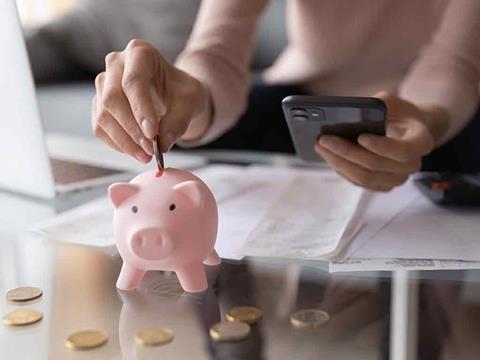 person putting a coin into a piggy bank
