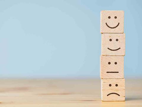 Wooden blocks with smiley, neutral and sad faces on